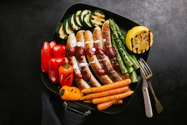 Saucisses avec sauce et légumes sur la poêle à frire