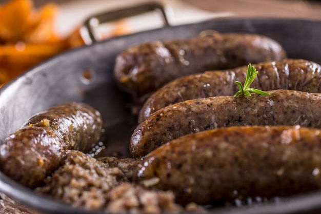 Saucisses.Saucisse de porc rôtie dans une poêle avec pommes de terre et romarin.