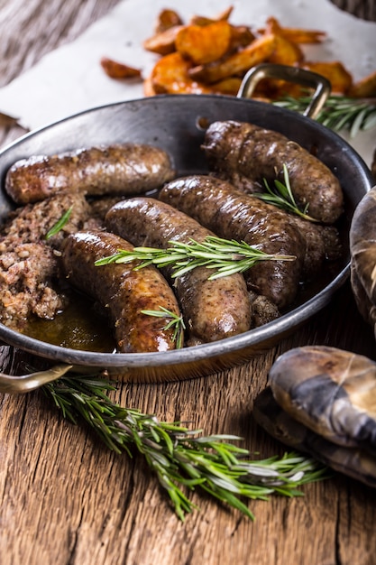 Saucisses.Saucisse de porc rôtie dans une poêle avec pommes de terre et romarin.