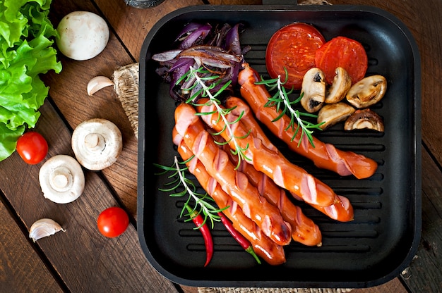 Saucisses sautées aux légumes sur une plaque blanche