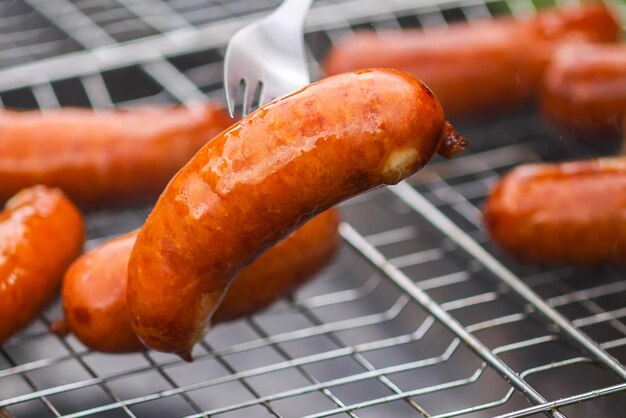 Saucisses savoureuses frites sur brazier avec des charbons ardents à l'extérieur dans la campagne en été Processus de cuisson Barbecue grill