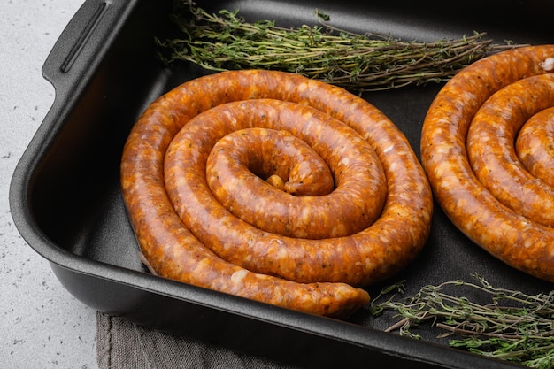 Saucisses en spirale allemandes brutes sur fond de table en béton gris