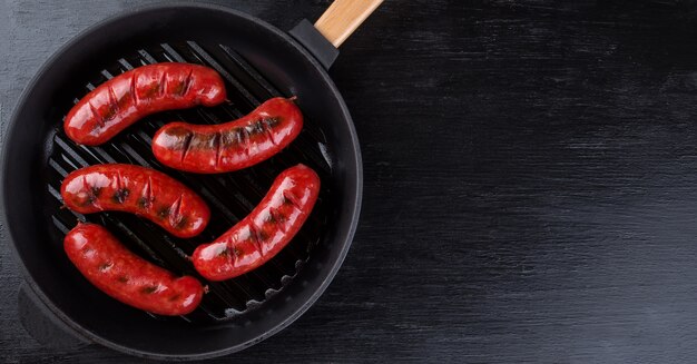 Saucisses de viande frites dans une poêle à griller