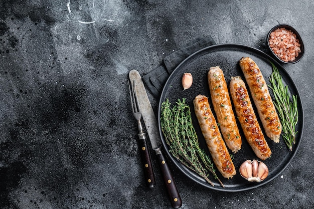 Saucisses de viande de porc rôties Bockwurst dans une assiette. Fond noir. Vue de dessus. Copiez l'espace.