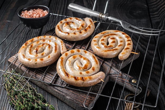 Saucisses de viande de porc en spirale grillées au barbecue sur un gril Fond noir Vue de dessus