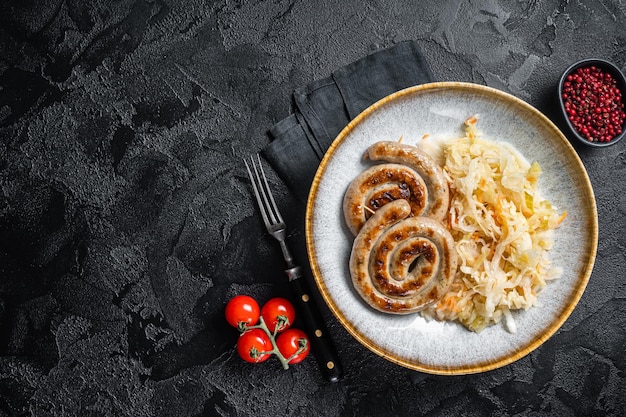 Saucisses de viande en spirale bavaroises rôties sur une assiette avec de la choucroute Fond noir Vue de dessus Espace de copie