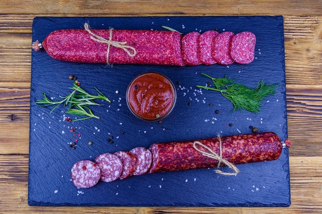 Saucisson de salami fumé sec en tranches sur une ardoise. Vue de dessus