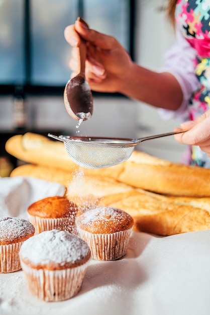 Sauger les cupcakes avec du sucre en poudre à travers un tamis