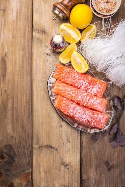 Le saumon est coupé en tranches et saupoudré de sel et d'épices, sur une planche de bois