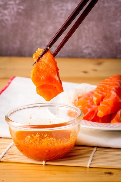 Le saumon frais est ramassé dans un bol de sauce aux fruits de mer avec une baguette en bois