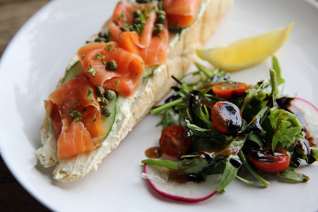 saumon fumé sur pain grillé avec crème fraîche, citron et salade