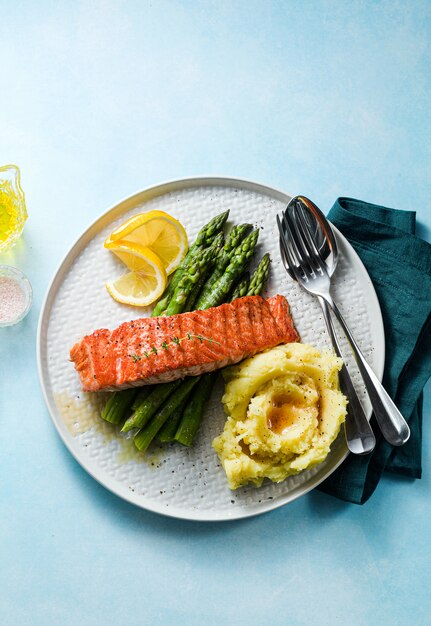 saumon grillé avec asperges fraîches et purée de pommes de terre dans une assiette. des aliments sains sur la table