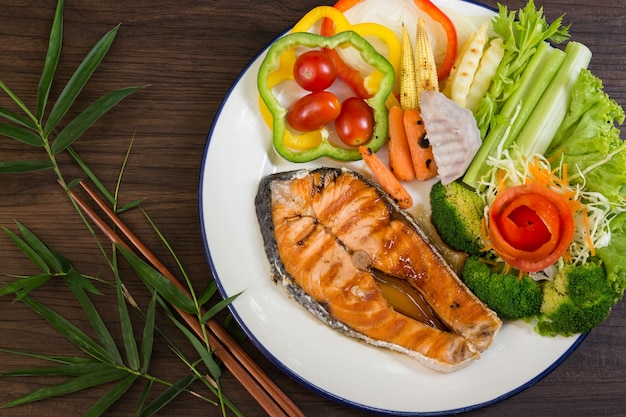 Saumon grillé avec des légumes mélangés sur fond en bois