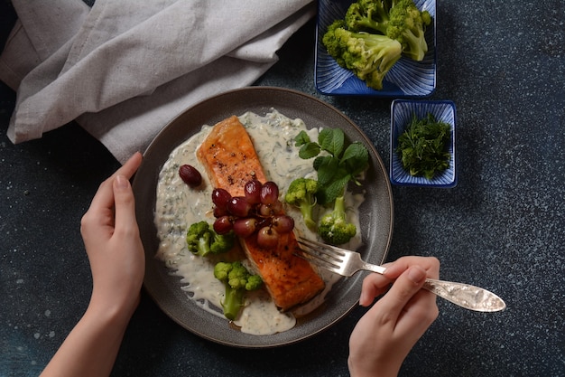 Saumon grillé avec raisins rouges rôtis et brocoli dans une sauce crémeuse à l'ail