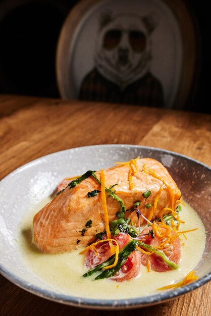 Saumon de poisson cuit au four avec sauce blanche aux carottes sur une table en bois dans un restaurant