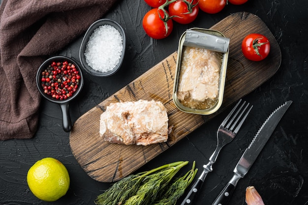 Saumon rose sauvage en conserve sur une planche à découper en bois sur fond noir avec des herbes et des ingrédients vue de dessus mise à plat