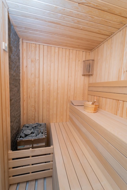 Un sauna en bois avec un panier sur le côté et un seau de charbon de bois sur le sol.