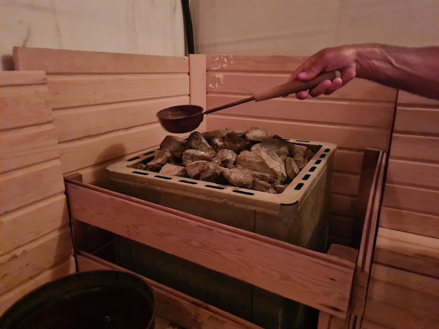 Sauna finlandais de station thermale et eau chaude de vapeur sur des roches