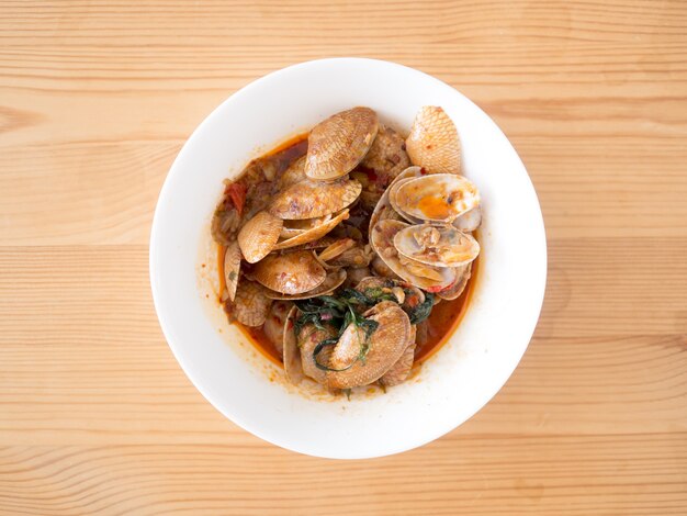 Sauté de Cramb avec Curry servi sur une table en bois.