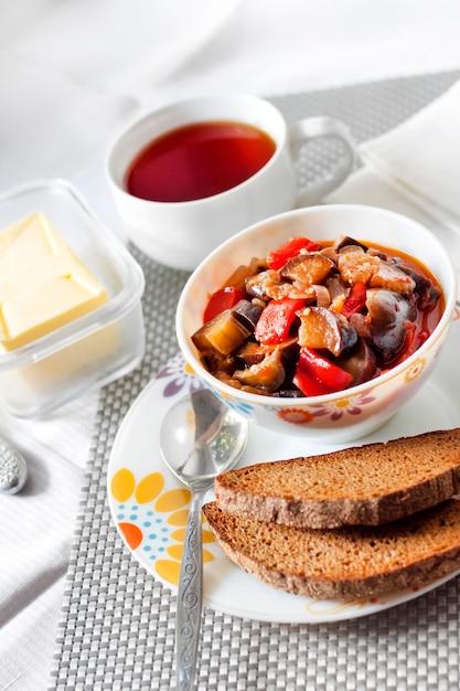 Sauté de légumes aux aubergines poivrons rouges et tomates et pain de seigle grillé sur une assiette