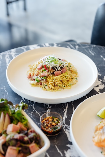 Sauté de nouilles chinoises avec jambon et chair de crabe sur la table en marbre noir.