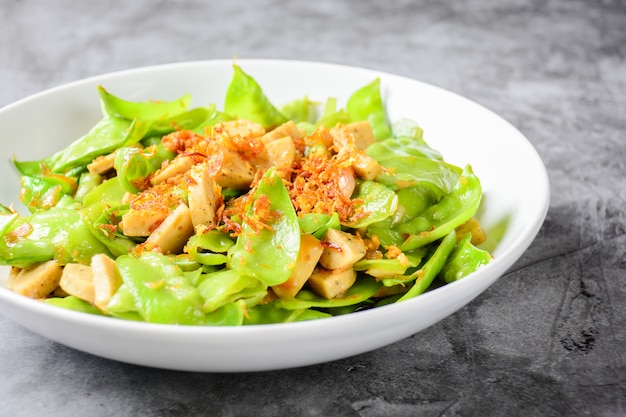 Sauté de pois mange-tout avec des saucisses de porc grillées vietnamiennes, garnies d'échalotes frites croustillantes et d'ailes