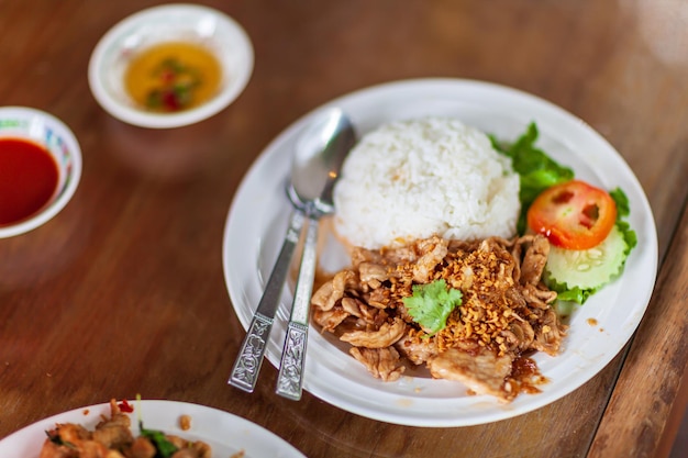 Sauté de porc avec du riz à l'ail dans une assiette blanche sur la table dresse un repas populaire en Thaïlande