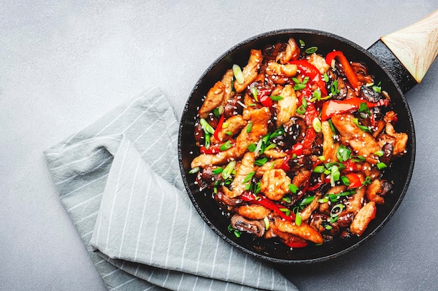 Sauté de poulet paprika rouge champignons et ciboulette dans une poêle à frire plat de cuisine asiatique table de cuisine gris fond vue de dessus espace de copie