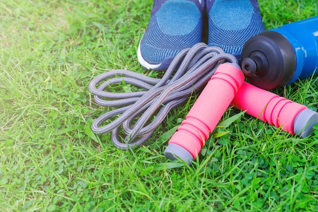 Sauter à la corde, chaussures de course et boire une bouteille sur fond d&#39;herbe