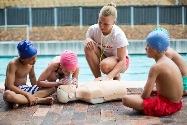 Sauveteur Féminin Aidant Les Enfants Pendant La Formation De Sauvetage Au Bord De La Piscine