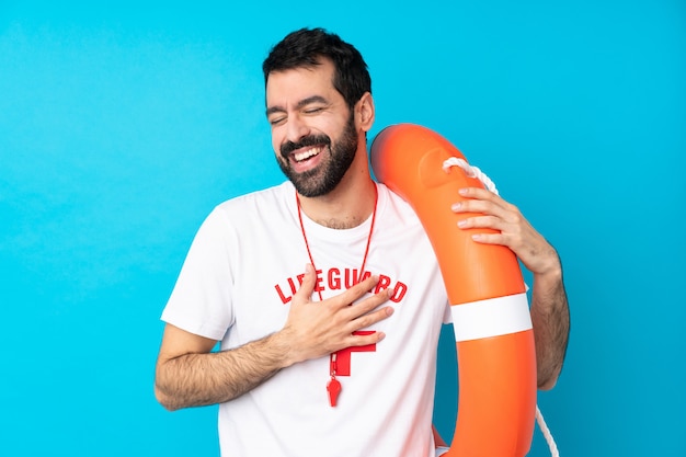 Sauveteur homme sur mur bleu isolé souriant beaucoup