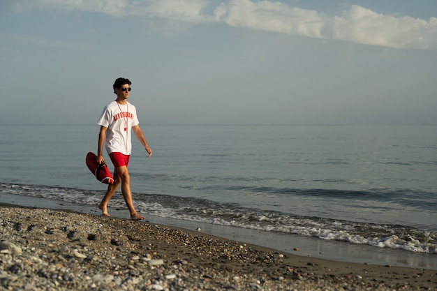 Photo sauveteur marchant sur la plage plein coup