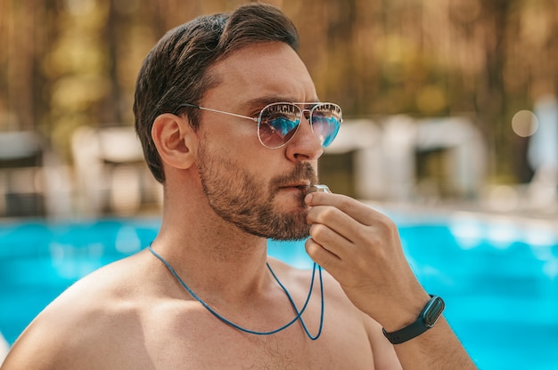 Sauveteur masculin dans des lunettes de soleil près de la piscine publique