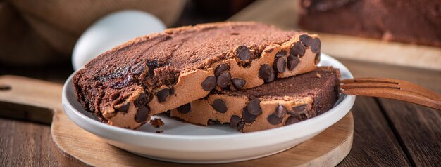 Saveur de chocolat gâteau éponge traditionnel taïwanais (castella kasutera taïwanais) sur un plateau en bois de fond de table avec des ingrédients, gros plan.