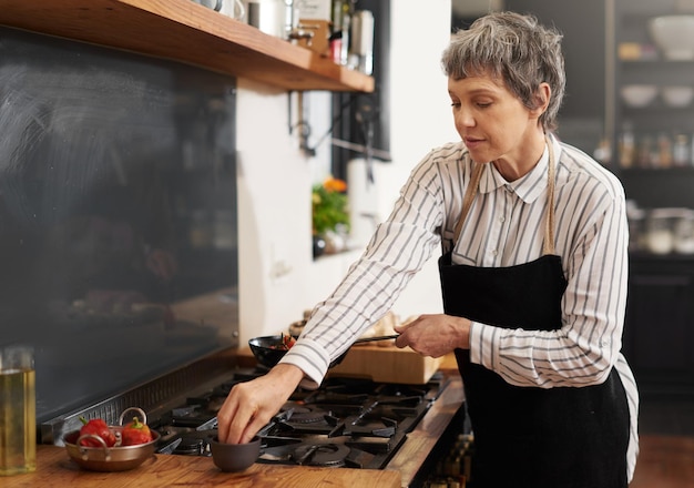 La saveur lui vient naturellement Photo d'une femme mûre cuisinant à la maison