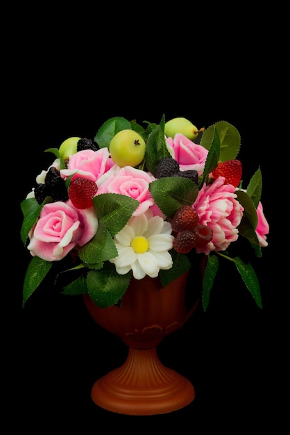 Savon artisanal exclusif sous forme de roses pivoines marguerites baies et fruits dans un vase sur fond noir.