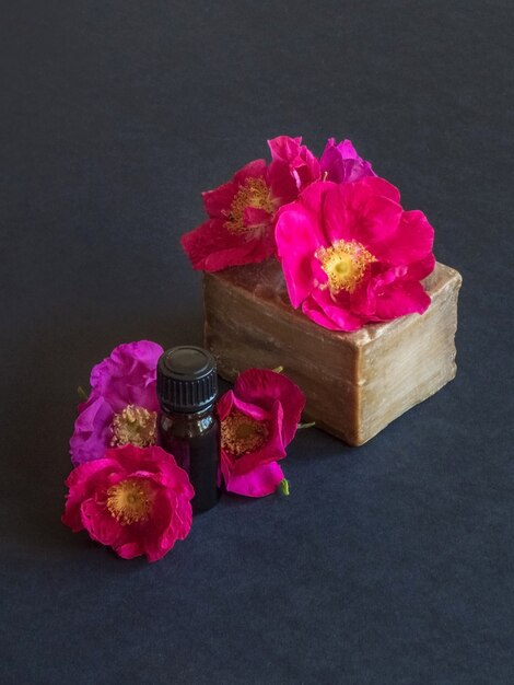 Savon artisanal et fleurs de roses sur un tableau noir.