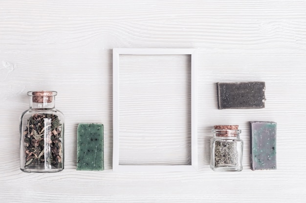 Savon artisanal avec des ingrédients biologiques naturels aux herbes aromatiques pour les soins du corps et le bien-être. Relaxation et zen comme concept. Composition de spa à plat sur une table en bois blanc avec espace de copie.