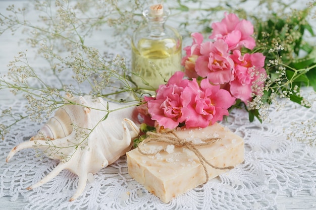 Savon artisanal naturel, huile aromatique et fleurs sur fond de bois blanc. Notion de spa.