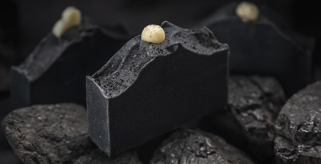 Savon au charbon de bois naturel sur de vrais charbons sur fond noir Concept de fabrication et d'utilisation de savon et de cosmétiques bio écologiques