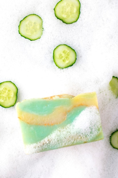 Savon au concombre sur fond de mousse blanche. Vue de dessus.