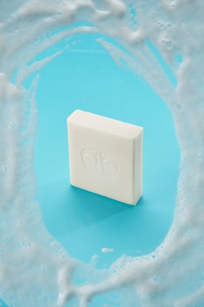 Savon bébé de couleur blanche sur fond bleu avec de la mousse de savon