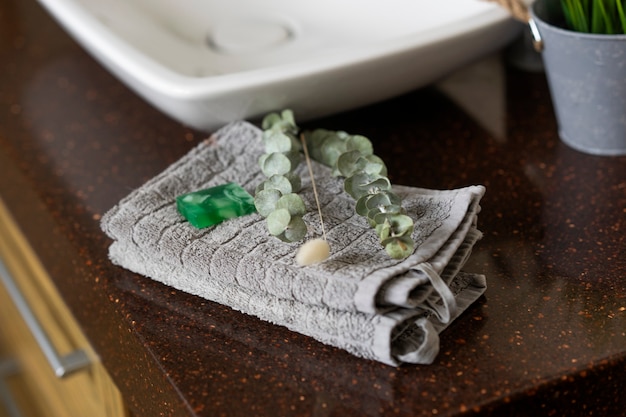Un savon fait à la main et une branche verte d'eucalyptus se trouvent sur une serviette en coton gris