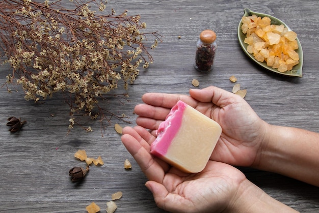 Savon fait maison sur la main de la femme pour la salle de bain bio fait à la main sur fond vintage en bois