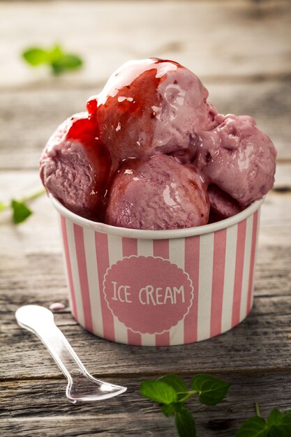 Savon à la fraise à la vanille savoureuse délicieuse avec de la confiture en tasse de papier rose sur une table en bois. Fermer.