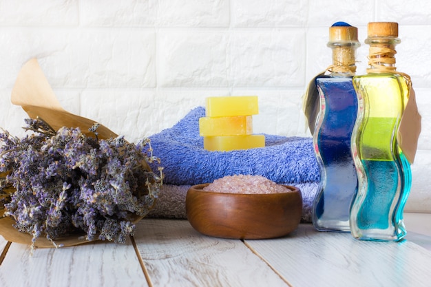 Savon à la lavande naturelle et sel de bain, huile française et serviettes sur un fond en bois blanc