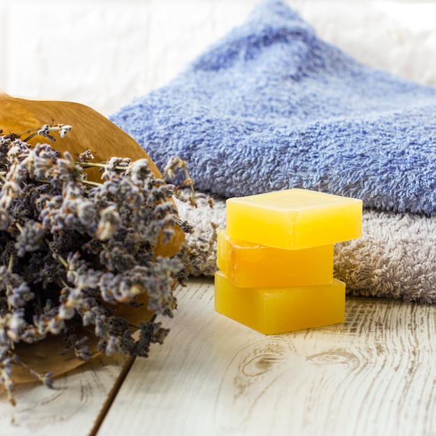 Savon à la lavande naturelle et sel de bain, huile française et serviettes sur un fond en bois blanc