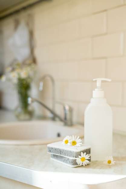 Savon à vaisselle écologique non toxique avec des fleurs de camomille pour nettoyer les assiettes blanches