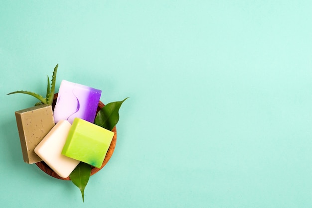 Savons de bar faits maison bio colorés à la main dans un panier avec des feuilles sur le vert