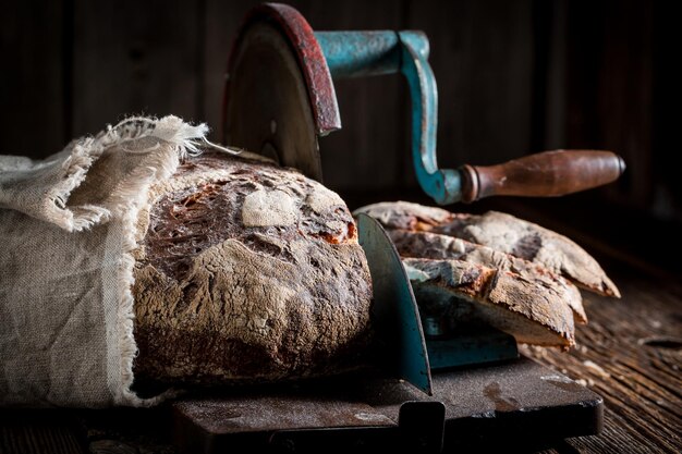 Savoureuse miche de pain sur une trancheuse avec sur une table sombre